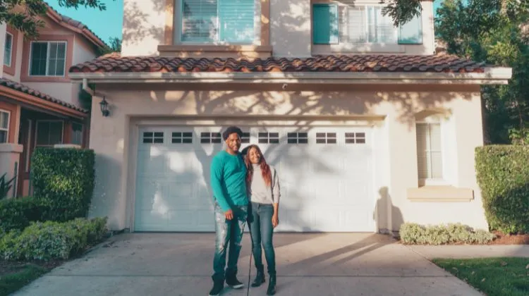 happy homeowners standing in front of their house