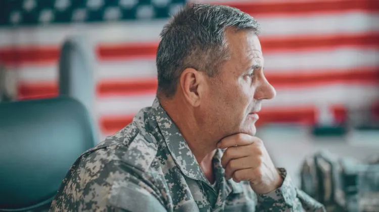 Servicemember sitting at desk with US flag in background