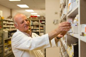 man in white dress shirt holding white paper in pharmacy
