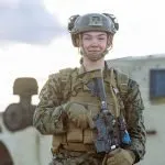 Young female marine in uniform with rifle and helmet